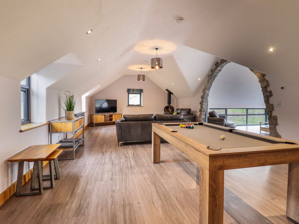A game room with a pool table and sofa at Granar in Llangwm near Bala