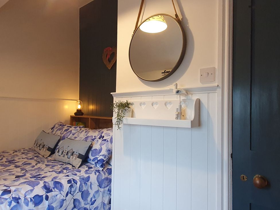 A bedroom with a bed and wall mirror at The Coach House in Prestatyn