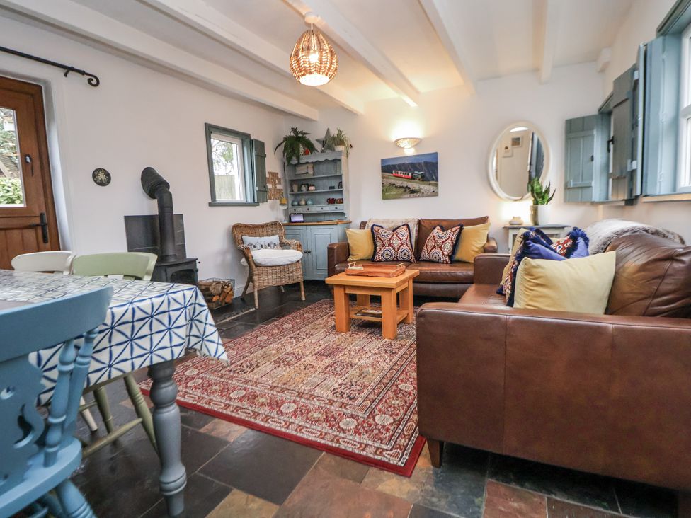A living room with a sofa, coffee table, and wood stove at The Coach House in Prestatyn