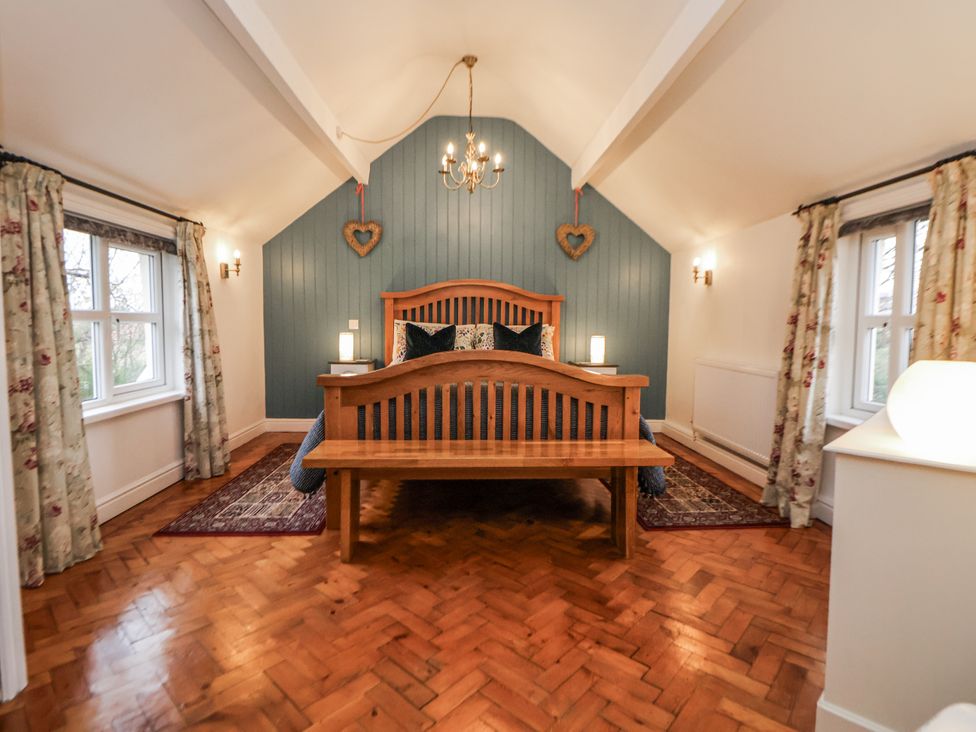A bedroom with a wooden bed and windows at The Coach House in Prestatyn