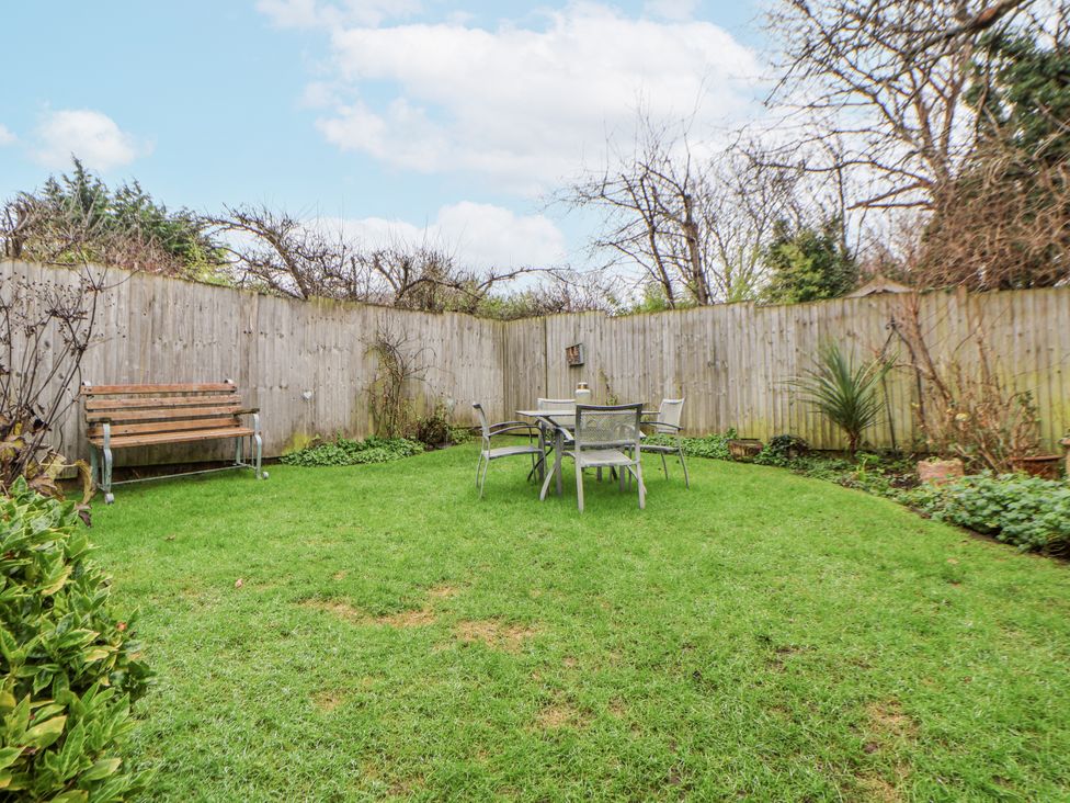 A garden with a table and chairs along with a bench at The Coach House in Prestatyn