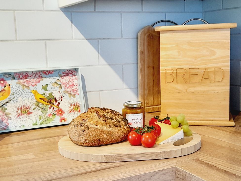 A kitchen with bread and cheese on a cutting board at Crab Cottage in Ilfracombe