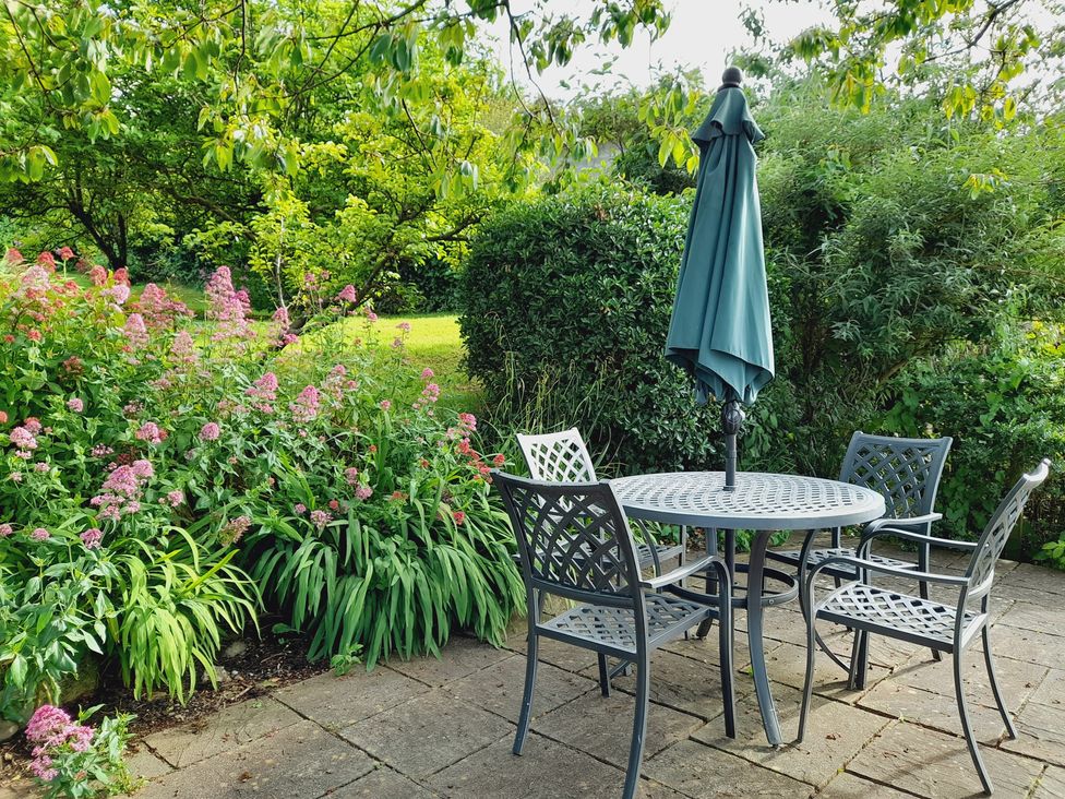 A garden with a table and chairs under an umbrella at Crab Cottage in Ilfracombe