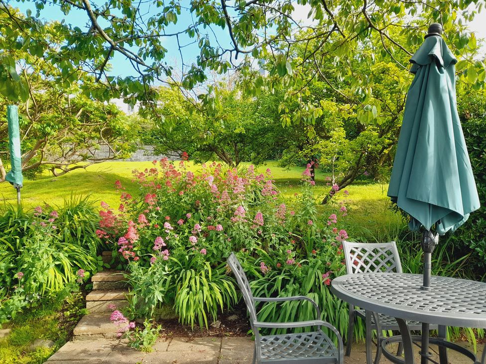 A garden with flowers and furniture at Crab Cottage in Ilfracombe