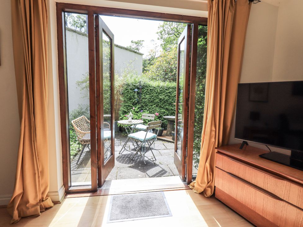 A living room with double doors opening to a garden at Doe Foot Cottage Ingleton