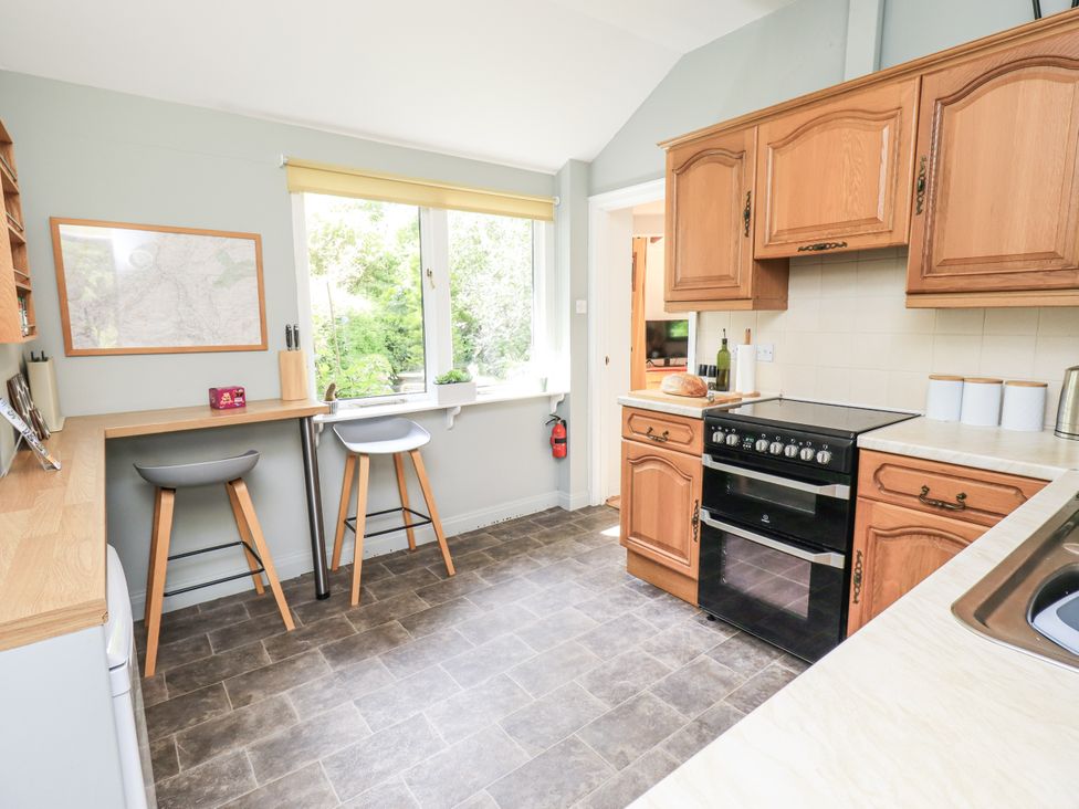 A kitchen with an oven and bar stools at Doe Foot Cottage Ingleton