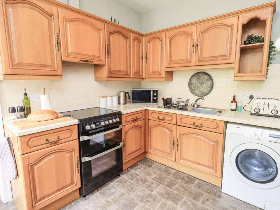 A kitchen with wooden cabinets and appliances at Doe Foot Cottage Ingleton