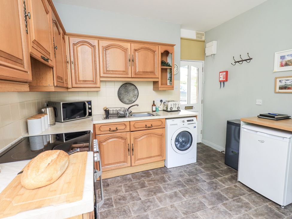 A kitchen with wooden cabinets and appliances at Doe Foot Cottage Ingleton