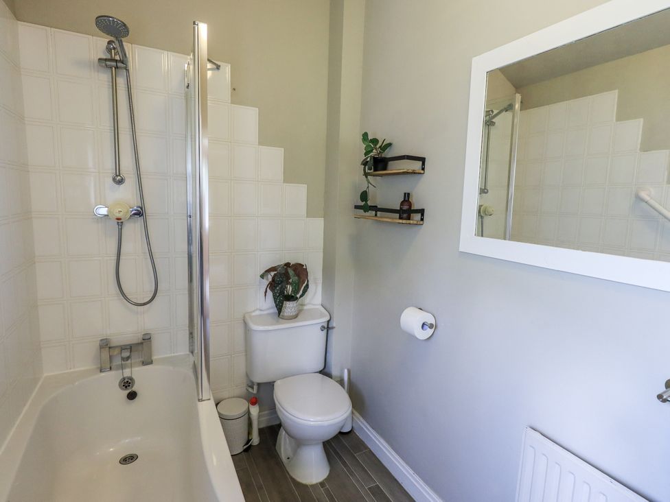 A bathroom with a shower, bathtub, toilet, and shelf at Doe Foot Cottage Ingleton