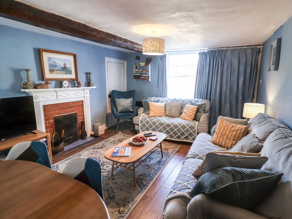 A living room with a sofa and armchair at Delphinium in Blakeney, Norfolk