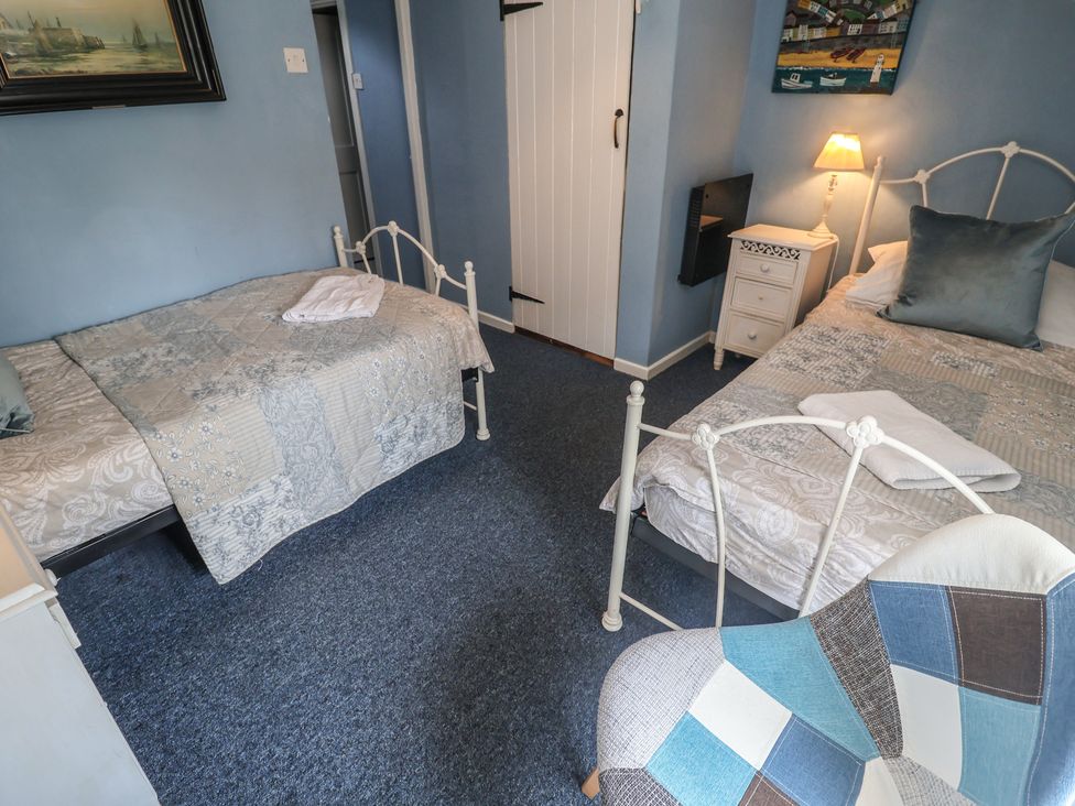 A bedroom with two beds and a nightstand at Delphinium in Blakeney, Norfolk