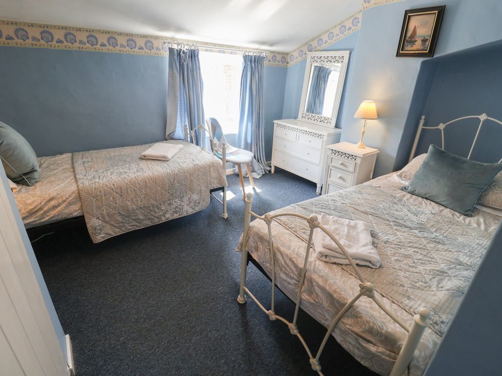 A bedroom with two beds and a dresser at Delphinium, Blakeney, Norfolk
