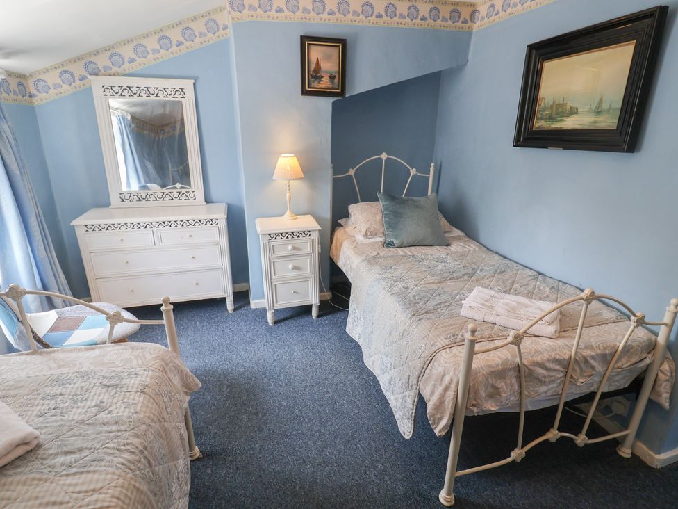 A bedroom with two beds and a dresser at Delphinium in Blakeney, Norfolk