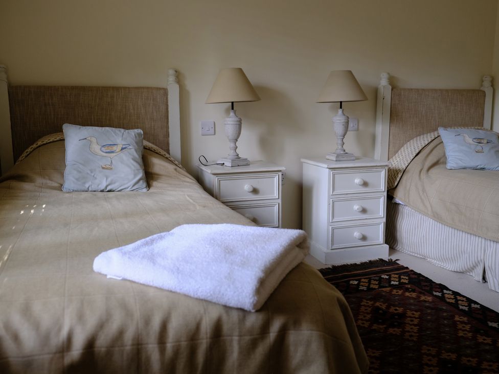 A bedroom with two single beds and bedside tables at Long Meadow in Midhurst