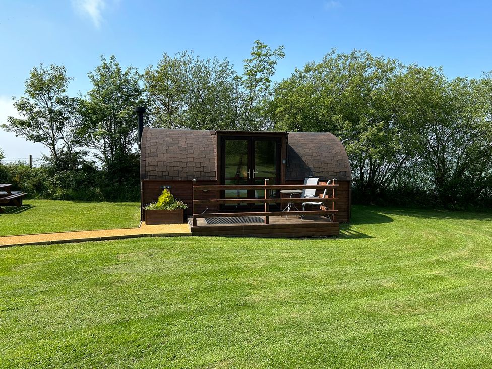 A wooden pod with decking and furniture at Gelert Pod St Asaph