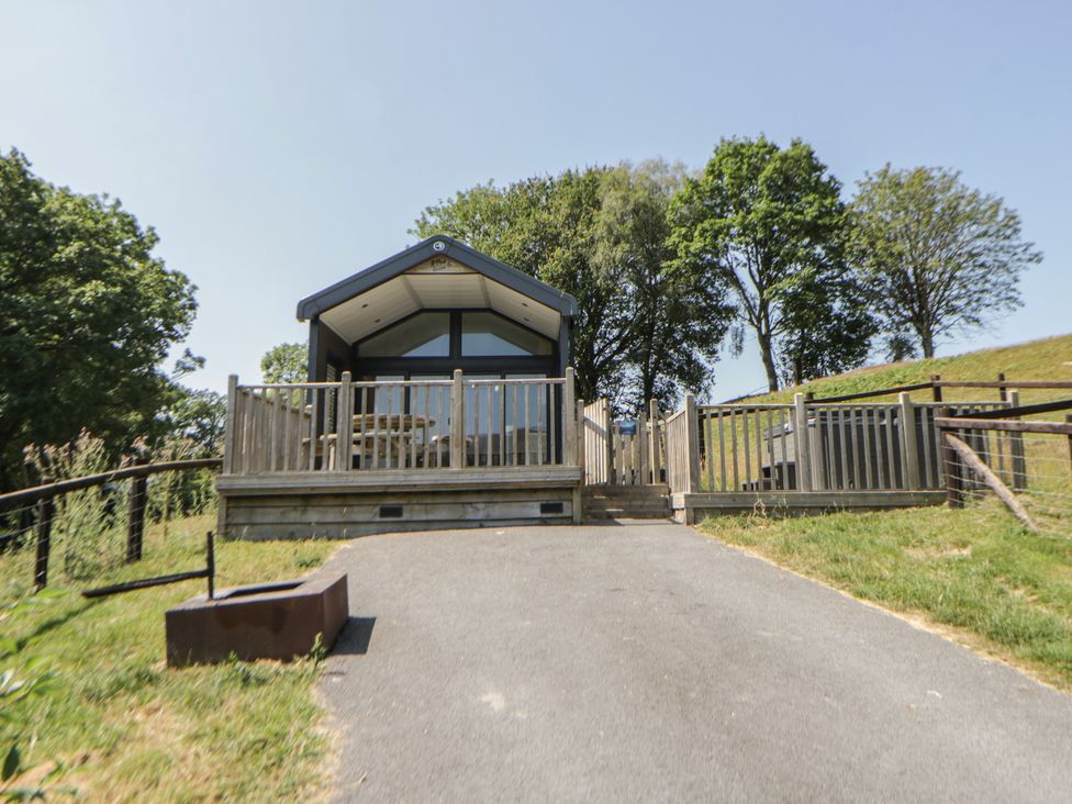 A house with a deck and trees at Hillside Lodge Nantmel near Rhayader