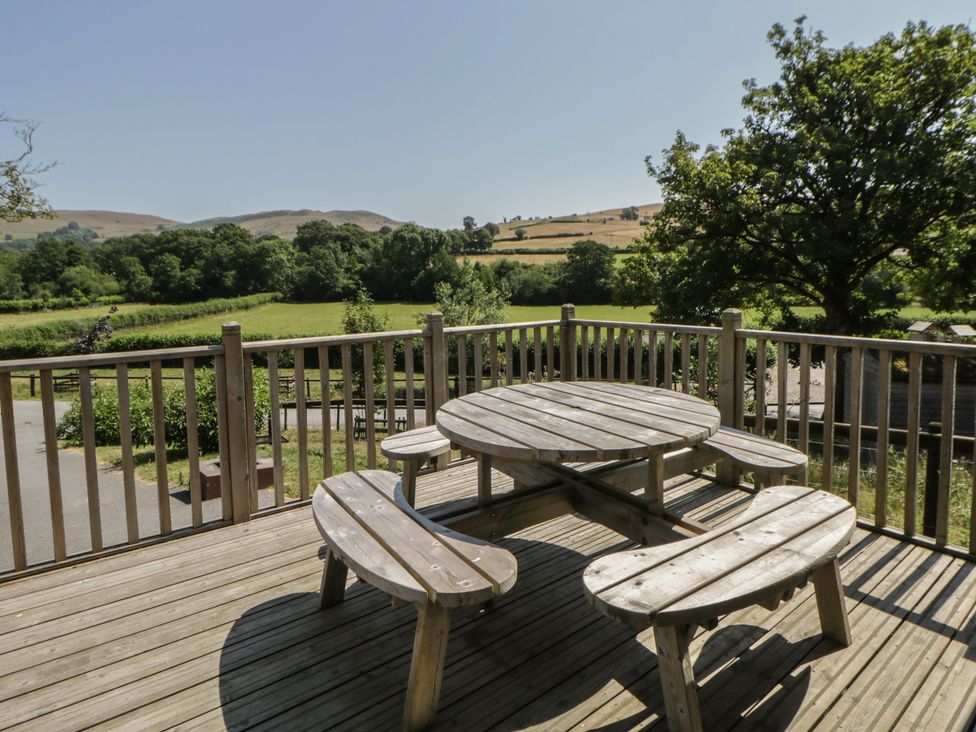 A deck with a wooden table and benches at Hillside Lodge Nantmel near Rhayader