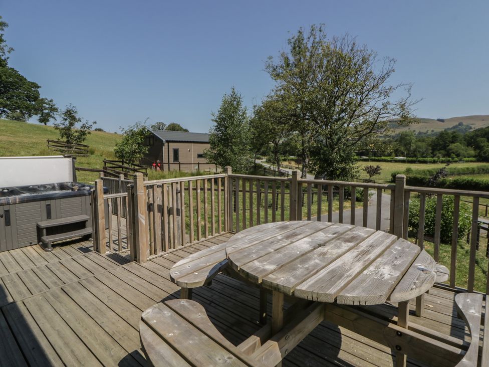 A wooden deck with a hot tub and seating area at Hillside Lodge in Nantmel near Rhayader