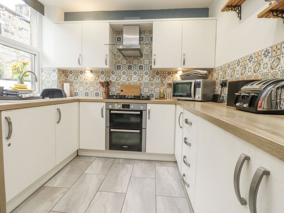 A kitchen with cabinets, countertop, stove, oven and microwave at Lorna Loom Skipton