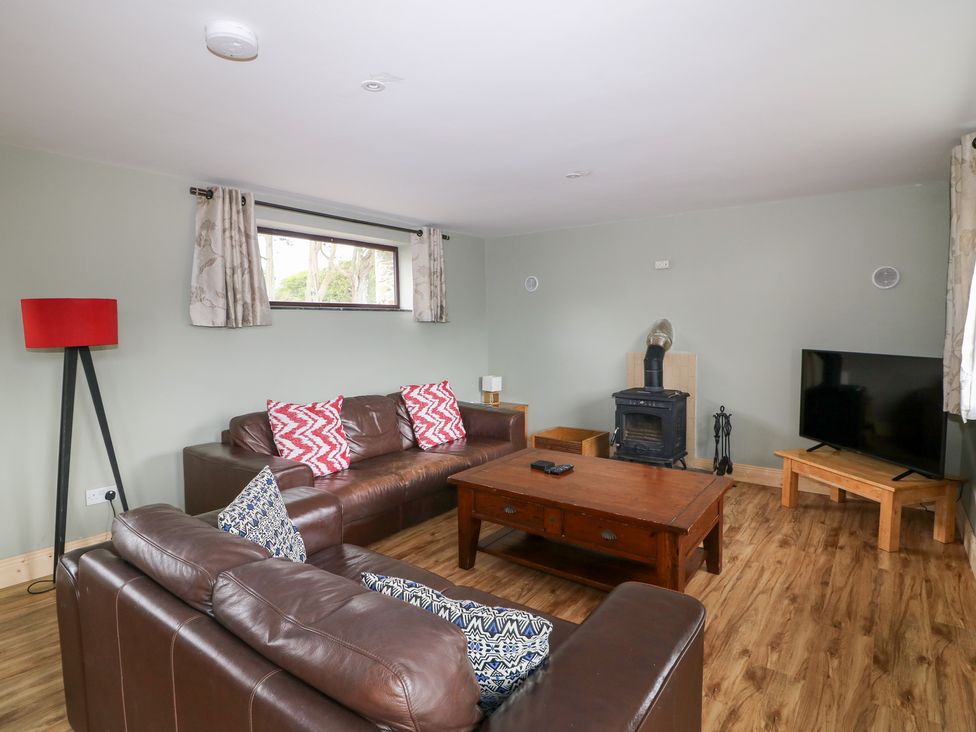 A living room with a sofa, coffee table, and television at The Owl's Hoot in Tacumshane, County Wexford