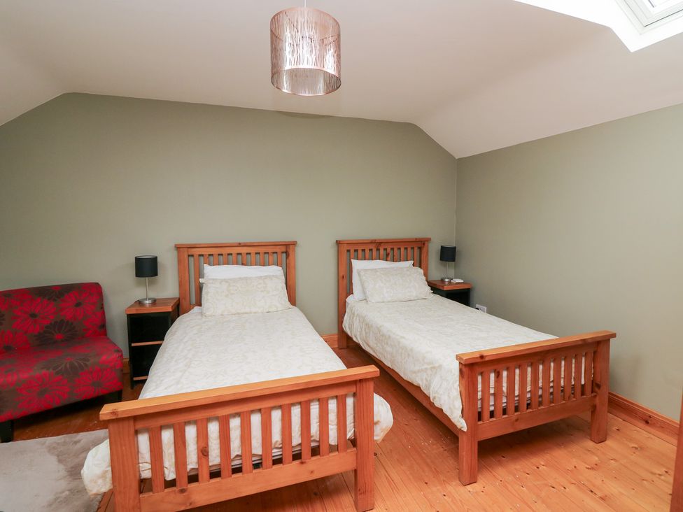A bedroom with two single beds and a sofa at The Owl's Hoot in Tacumshane, County Wexford