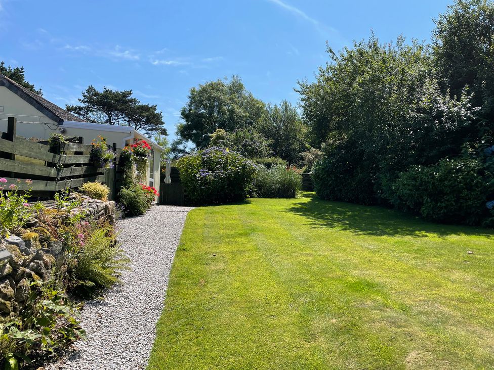A garden with grass and flowers at Garden Cottage St Just