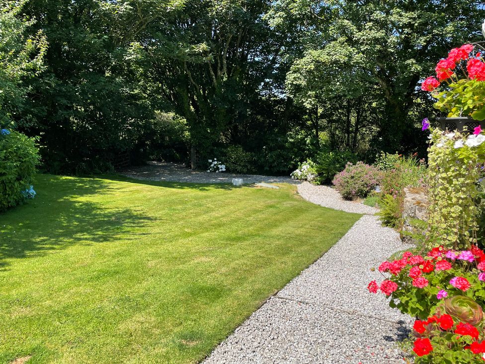 A garden with a lawn and flower beds at Garden Cottage in St Just