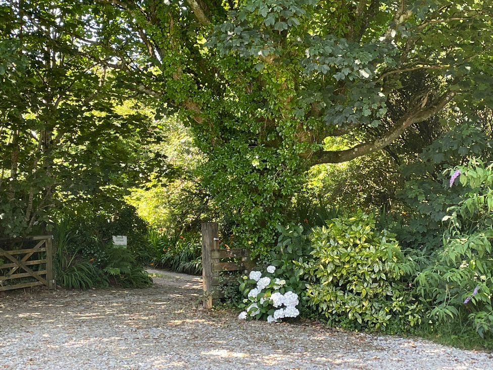 A garden path with a wooden gate and flowers at Garden Cottage in St Just