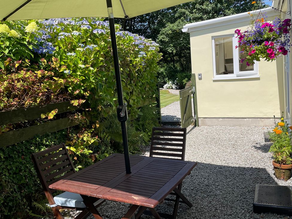 An outdoor seating area with a table and chairs at Garden Cottage St Just
