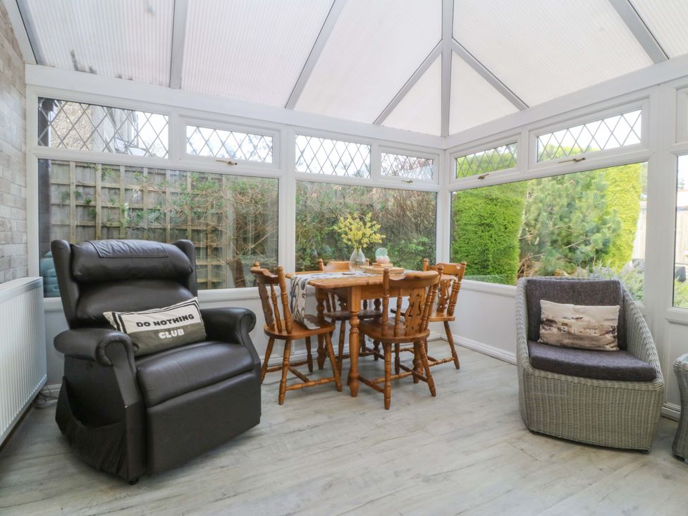 A conservatory with a dining table and chairs at The Cottage in Marian-Glas