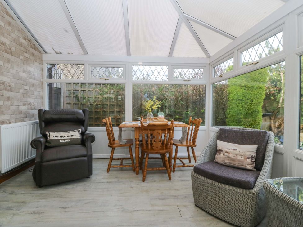 A conservatory with a dining table and chairs at The Cottage in Marian-Glas