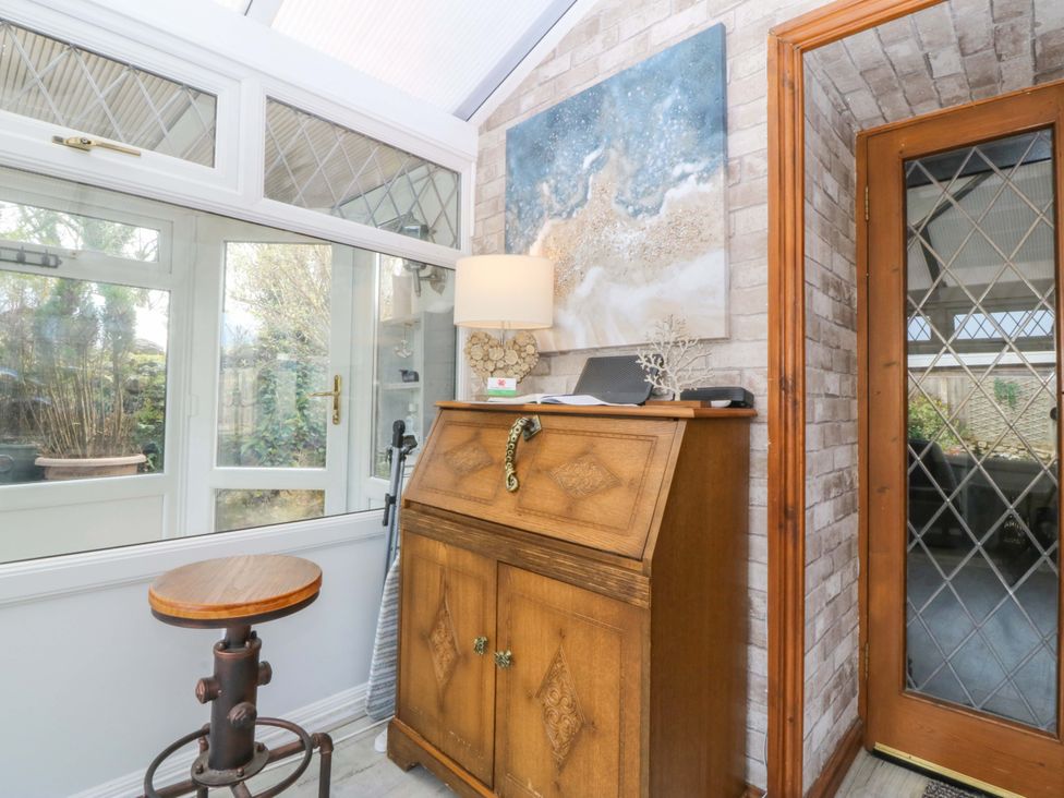 A conservatory with a wooden cabinet and a stool at The Cottage in Marian-Glas