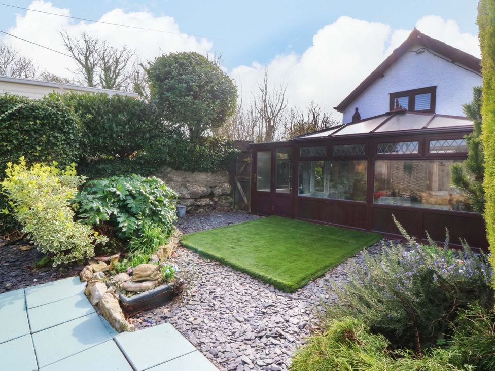 A garden with plants and a conservatory at The Cottage in Marian-Glas