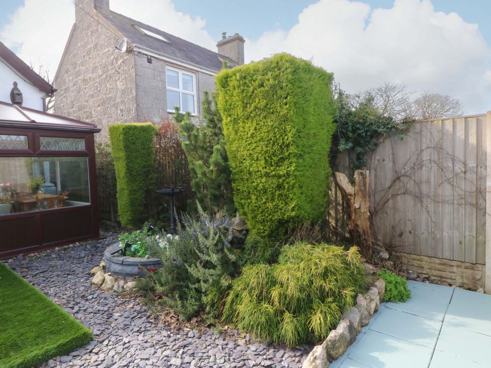 A garden with hedges and a conservatory at The Cottage Marian-Glas