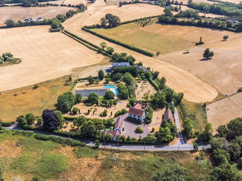 An aerial view of a property with a swimming pool and surrounding fields at Lower Tundridge Cottage Suckley near Malvern