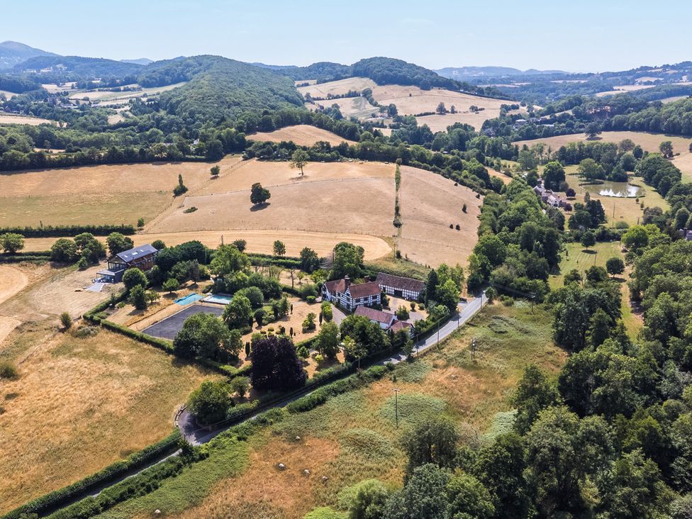 An outdoor area with a house, pool, and fields at Lower Tundridge Cottage in Suckley near Malvern