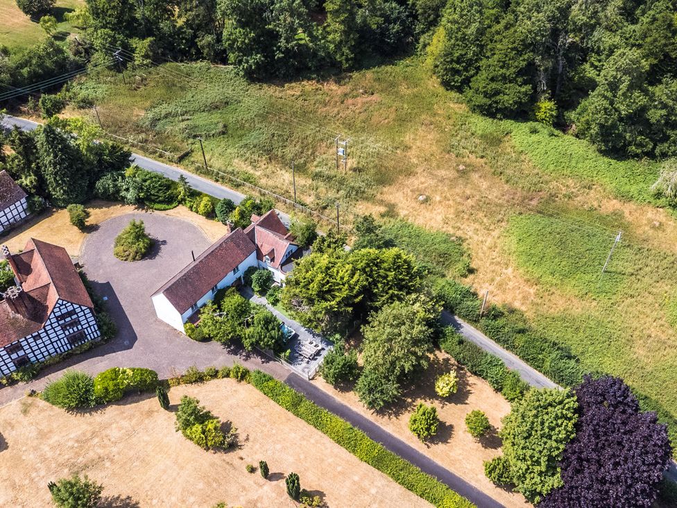 An outdoor view of a house with a garden and parking area at Lower Tundridge Cottage in Suckley near Malvern