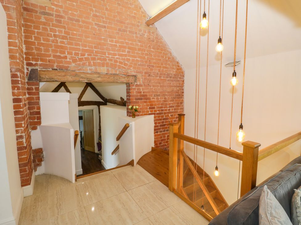 A staircase with wooden railing and hanging lights at Lower Tundridge Cottage Suckley near Malvern