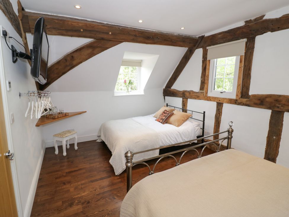 A bedroom with two beds and a television at Lower Tundridge Cottage, Suckley near Malvern