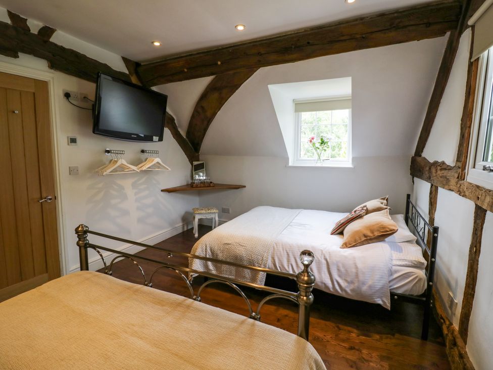A bedroom with a bed, television, window, and shelf at Lower Tundridge Cottage Suckley near Malvern