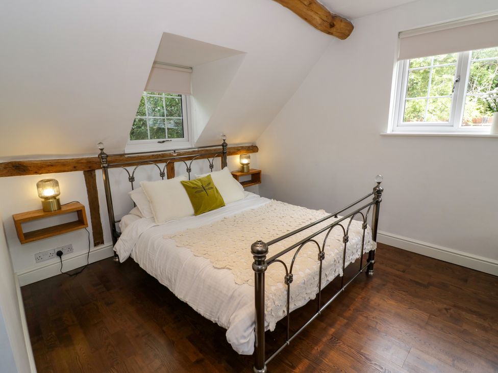 A bedroom with a metal bed and wooden beams at Lower Tundridge Cottage in Suckley near Malvern