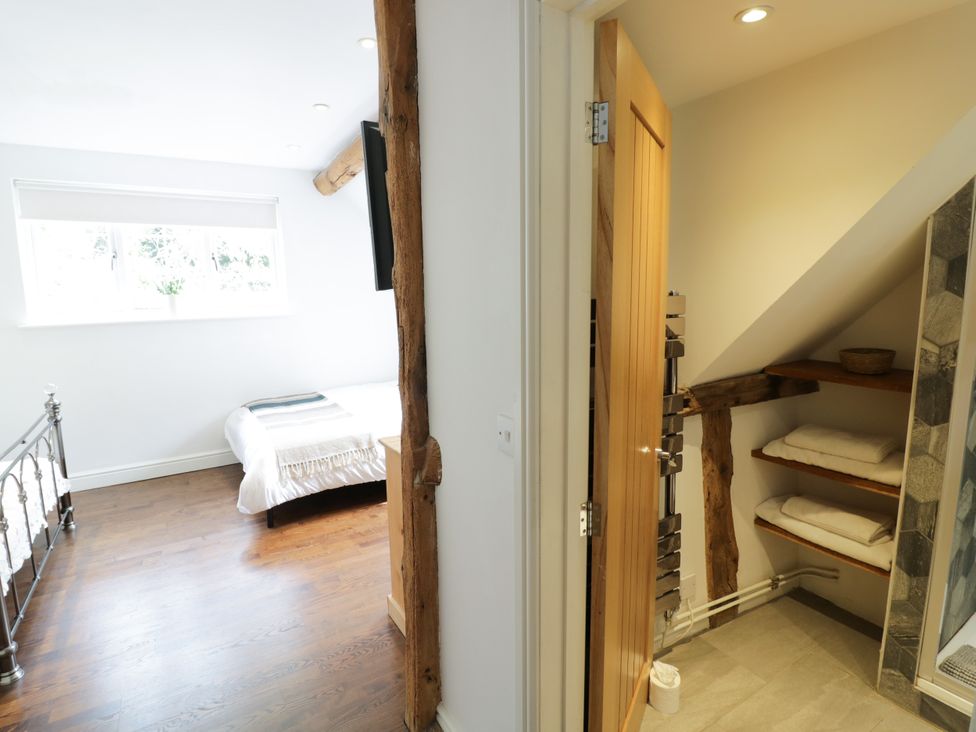 A bedroom with a bed and a door leading to a bathroom at Lower Tundridge Cottage Suckley near Malvern