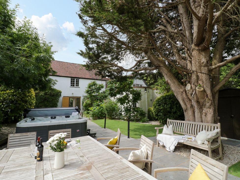 A garden with a dining table and hot tub at Lower Tundridge Cottage Suckley near Malvern