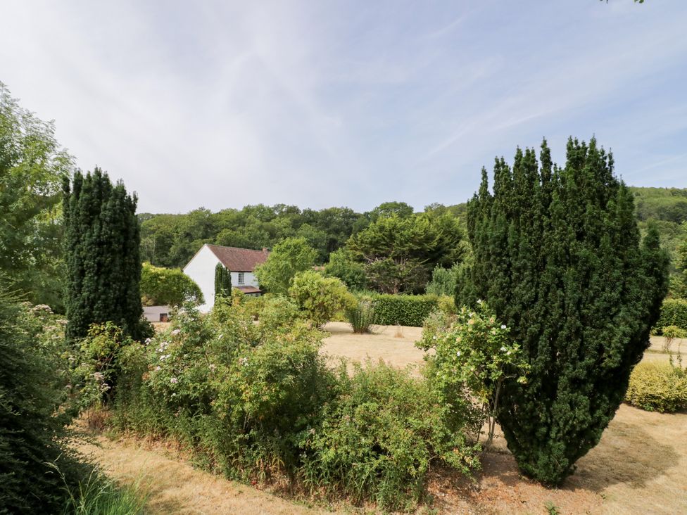 A garden with a house and trees at Lower Tundridge Cottage in Suckley near Malvern