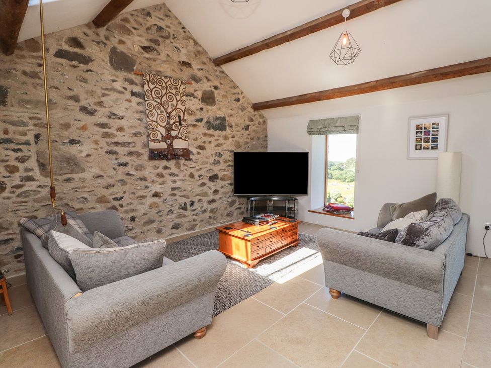 A living room with sofas and a television at Wern Olau Cottage in Groeslon near Caernarfon
