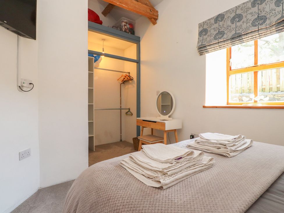 A bedroom with a bed and wardrobe at Wern Olau Cottage in Groeslon near Caernarfon