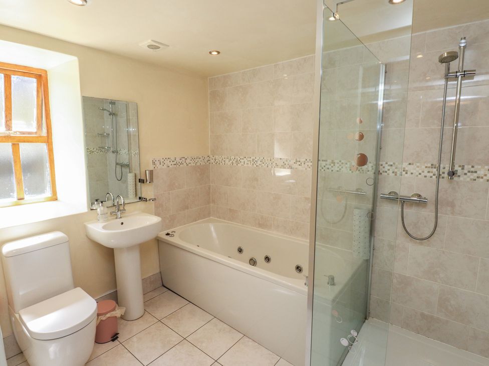 A bathroom with a sink, toilet, shower, and a bathtub at Wern Olau Cottage in Groeslon near Caernarfon