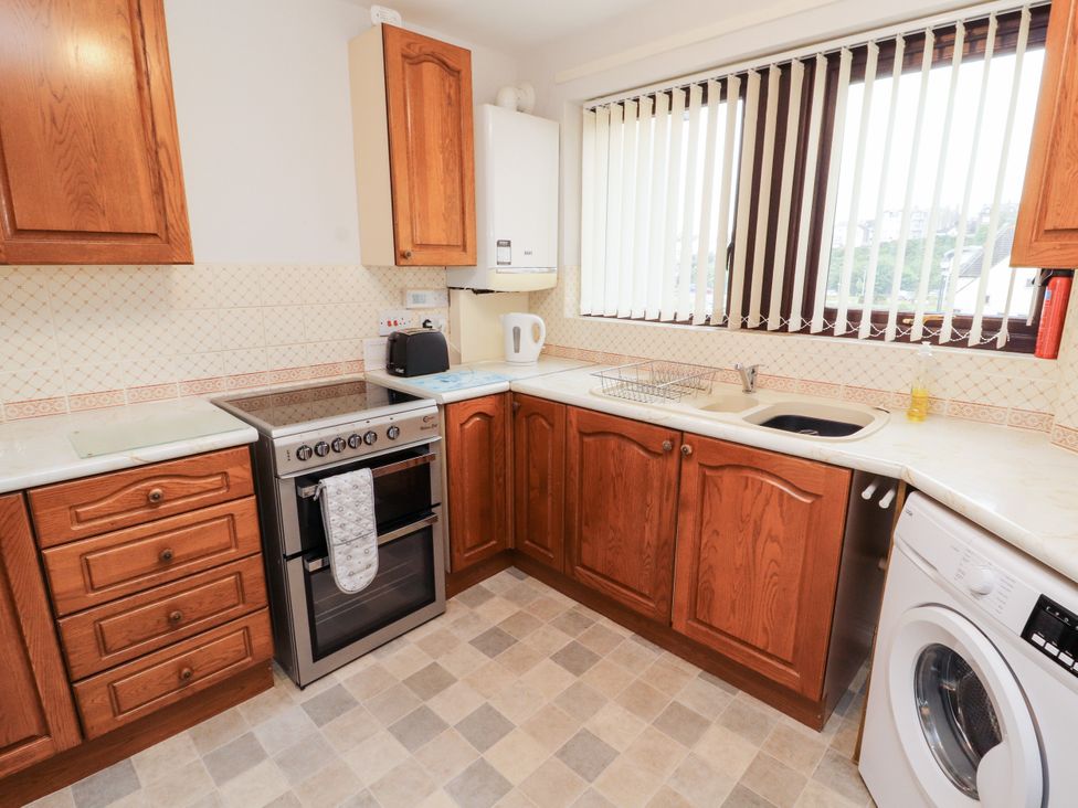 A kitchen with cabinets, an oven, and a washing machine at Harbour Side in Maryport
