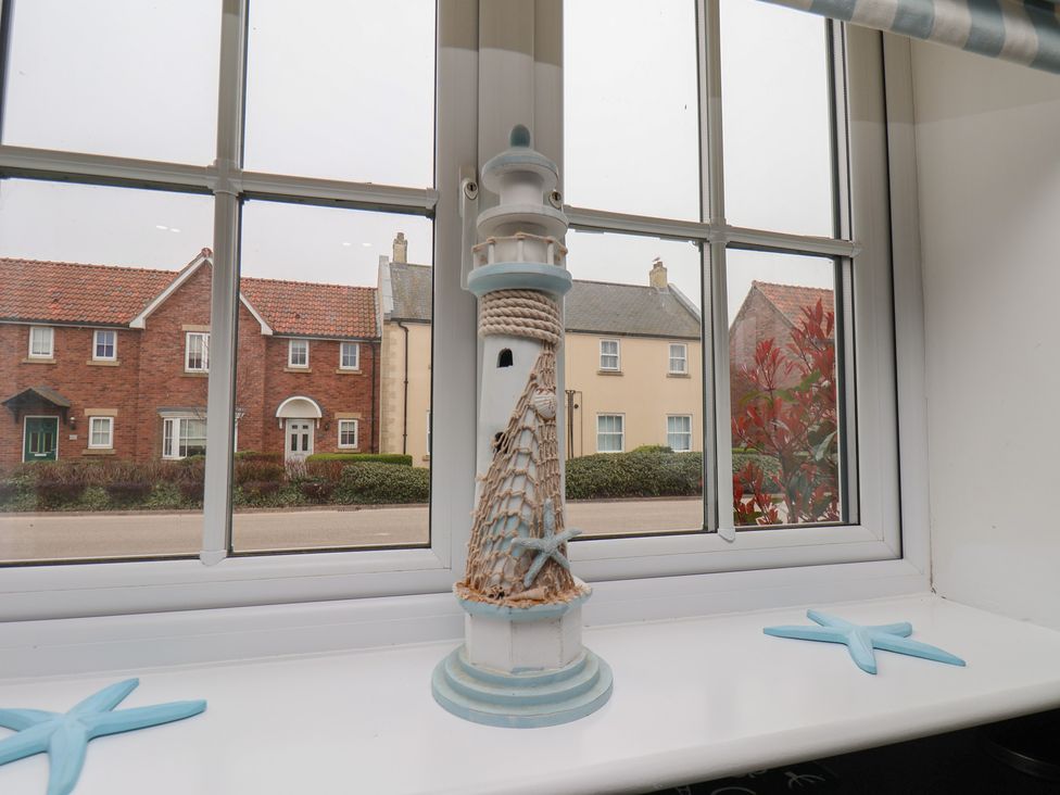 A lighthouse ornament on a windowsill with a view of houses at Coastal Cottage The Bay near Filey