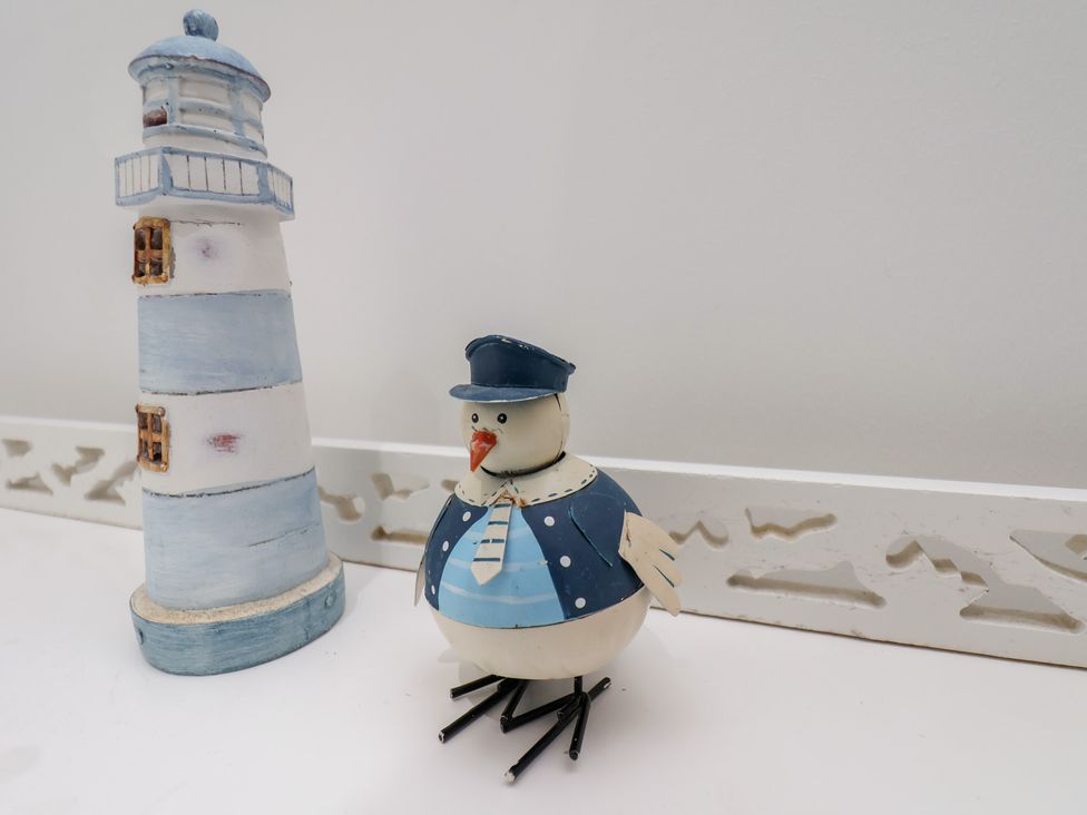 A lighthouse and a decorative bird on a shelf at Coastal Cottage The Bay near Filey
